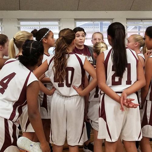 girls basketball team gathered around coach